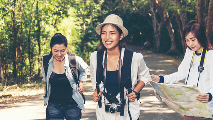 Group women traveler with backpack adventure holding map to find directions and walking relax in the jungle forest outdoor for destination leisure education nature on vacation.