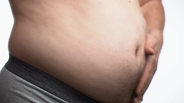 Hands of obese man touching his fat tummy. Close up of fat man shaking his stomach. Adult play with his fat belly.