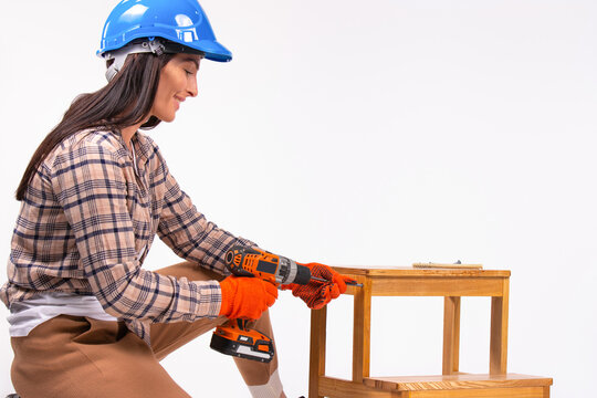 Young woman in a blue hard hat with a screwdriver on a white background. Gender stereotypes.