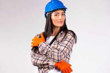  Young female mechanic in hard hat and protective builder gloves posing on a gray background. Gender equality, fearless, strong .