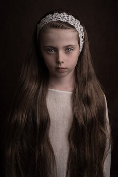 Intense studio portrait of a girl in white with long hair with ribbon in classic painterly style
