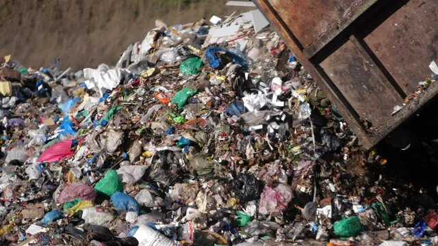 A dump truck unloads a pile of garbage at a landfill in slow motion. Dump of unsorted waste.