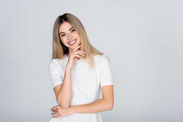 cheerful young woman in white outfit smiling isolated on grey