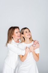 happy mother hugging young daughter isolated on grey, generation of women