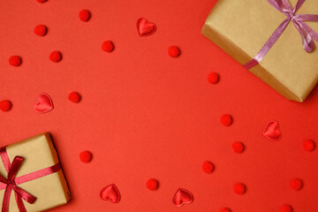 Flat lay. Valentine's Day. Gift boxes and hearts are laid out along the perimeter. Red background.