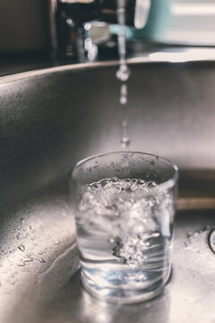 gotas de agua cayendo del grifo en un vaso