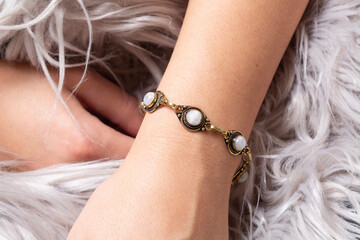 Female hand wrist wearing brass golden bracelet with moon stone mineral stone - 405809276