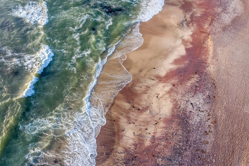 Küste von Namibia aus der Luft aufgenommen. Roter Sand aus der angrenzenden Namib Wüste, der...