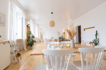 cute cozy light interior design of the apartment with a free layout of the kitchen and bedroom areas. a lot of windows, a wooden floor and a hanging swing.