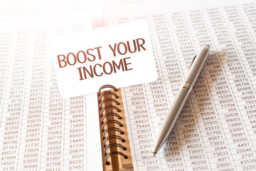 Text boost your income on paper card,pen, financial documentation on table - business, banking, finance and investment concept. close up of stock market chart.
