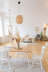 cute cozy light interior design of the apartment with a free layout of the kitchen and bedroom areas. a lot of windows, a wooden floor and a hanging swing.