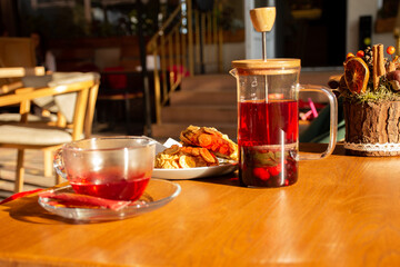 teapot with freshly brewed berry tea and cake on the table in a cafe