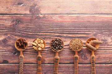 Spices and herbs on spoon on table, top view 