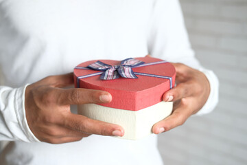 man's hand holding a gift box close up 