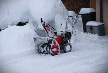 Snow blower to clear deep snow on driveway near residential house after heavy snowfall