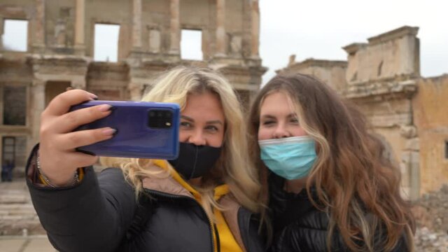 Traveling during the Covid-19 pandemic. A woman in a mask takes a selfie photo against the backdrop of attractions. Ruins of the ancient Greek city of Ephesus in Turkey. Taking pictures of himself.