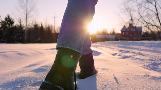 Legs of man walking on snow with footprints on snowy day