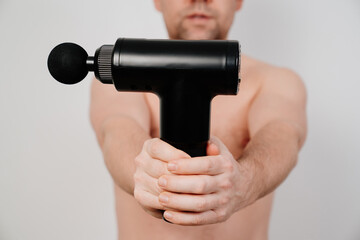 Fototapeta na wymiar focus on the subject. man holds massage gun. medical-sports device helps to reduce muscle pain after training, helps to relieve fatigue, affects problem areas of body, improves condition of skin.