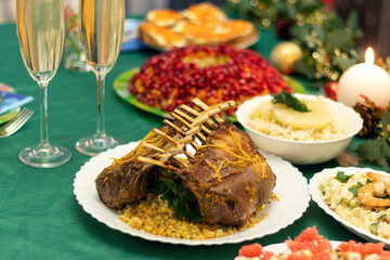A festive table with many delicious dishes. Lamb rack, two glasses of champagne, salads and snacks on the festive table.