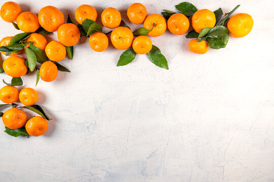 Orange tangerines with green leaves on a white stone background. View from above. Copy space. © Yelena Shander