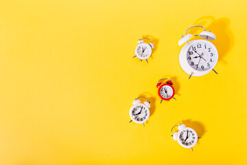 Image of 4 white and 1 red alarm clocks on isolated orange background