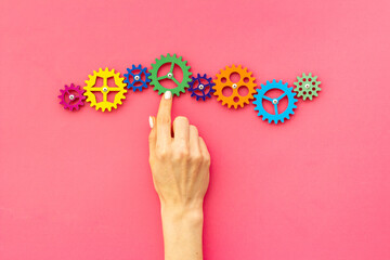 Teamwork concept. Hand connecting gears into puzzle - symbol of working mechanism