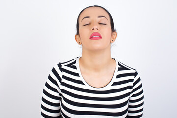 Young beautiful woman wearing stripped t-shirt against white background looking sleepy and tired, exhausted for fatigue and hangover, lazy eyes in the morning.