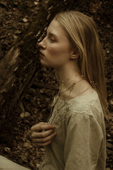 Portrait of a beautiful mysterious woman with blond hair in the forest.  like a fairytale. Warm tone