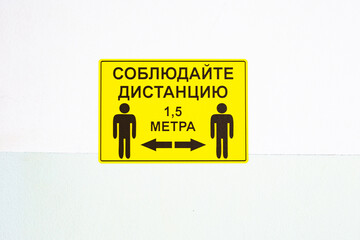 Yellow warning sticker on the wall in the hospital with the translation text - keep a distance of...
