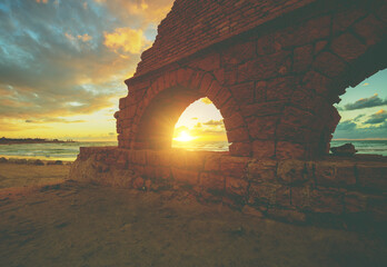 Remains of the ancient Roman aqueduct in ancient city Caesarea at sunset. Israel.