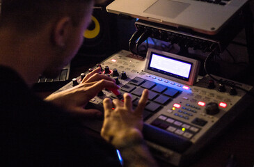 Beatmaker producing some beats with a drum machine in his home studio