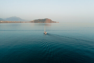 Sailboat on the sea in the morning breeze over beautiful big mountain background, summer adventure, active vacation in Mediterranean sea, Turkey