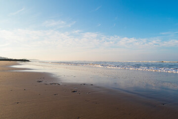 relaxing and gentle calming waves flowing into a beach at sundown, with a vivid blue sky and reflection. calming fresh air walks into nature during corona virus lockdowns