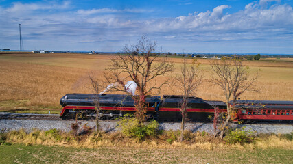 Aerial View of a Restored Antique Steam Locomotive Pulling Passenger Cars on a Sunny Fall Day