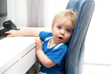 Little baby boy playing with computer and he is surprised. Children, technology online education concept.