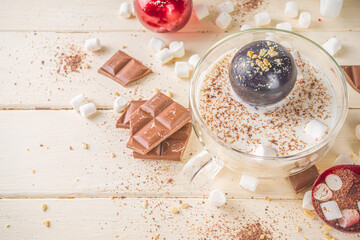 Hot chocolate bomb, with marshmallow and chocolates and nuts,  Woman's hand dropping chocolate bomb...