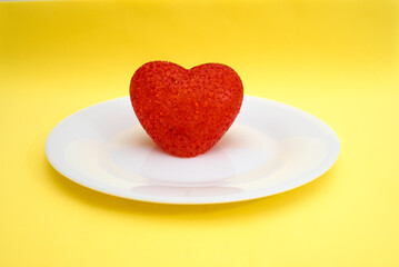 Obraz na płótnie Canvas Red heart on a white plate on a yellow background