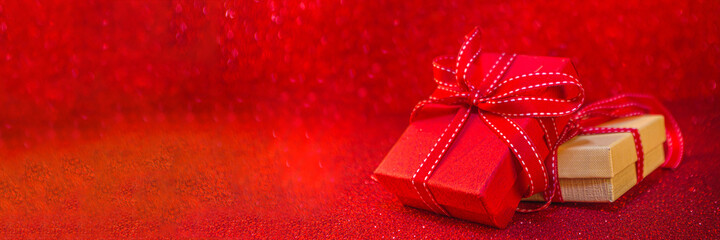 Valentine's day background. Red gift boxes with festive ribbon, on red bokeh shiny background. Birthday greeting card, valentine's day