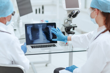 doctors looking at the Chest x-ray scan on screen of laptop .