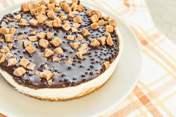 Cheesecake decorated with salted caramel pieces on light rustic background. Homemade dessert for birthday, festive party, engagement or Valentine day, selective focus, copy space