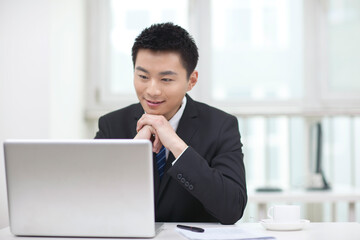 Portrait of businessman sitting and kooking at laptop