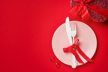 Valentines day background or concept with empty pink plate and whiteware on scarlet or red background. Top view flat lay with copy space.
