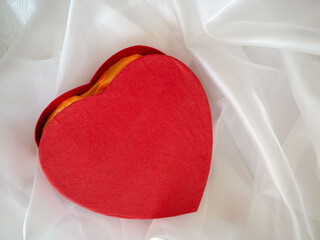red heart-shaped box on silk draped surface, close-up