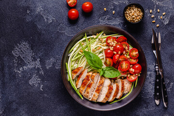 Fried chicken fillet and fresh vegetable salad of tomatoes, zucchini and pine nuts.