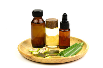 Lemongrass oil in bottle and fresh lemongrass sliced in wooden plate isolated on white background.