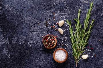Herbs and condiments on black stone background.