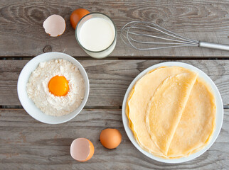 Flat composition with thin pancakes on wooden background