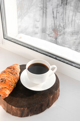 Top view of a cup of coffee, fresh croissant and knitted plaid on the wooden table. Cozy and warm flat lay with copy space. Time for a break.