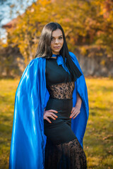 Woman in blue cloak and black dress, costumes for ladies. Girl in glamourous mascaraed dress