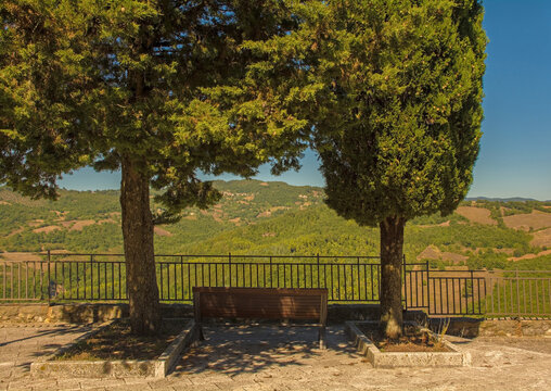 A shady bench by Rocca Aldobrandesca fort in the historic medieval village of Semproniano in Grosseto Province, Tuscany, Italy
